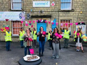 Buxton Street by Street coordinators and volunteers wearing high-vis yellow jackets and waving flags outside Connex building.